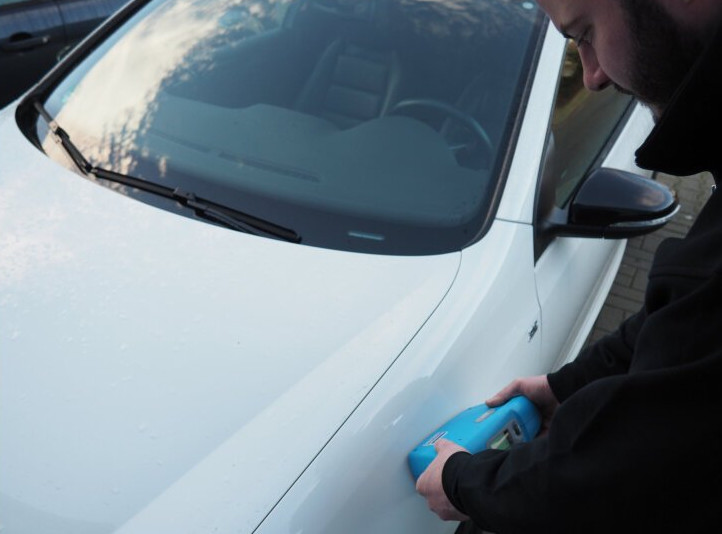 Farbtonmessung mit dem Messgerät an einem weißen Auto